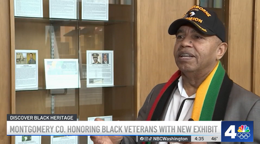 Commissioner Elwood Gray gives an interview in front of the veterans display cases at the Silver Spring Civic Building.