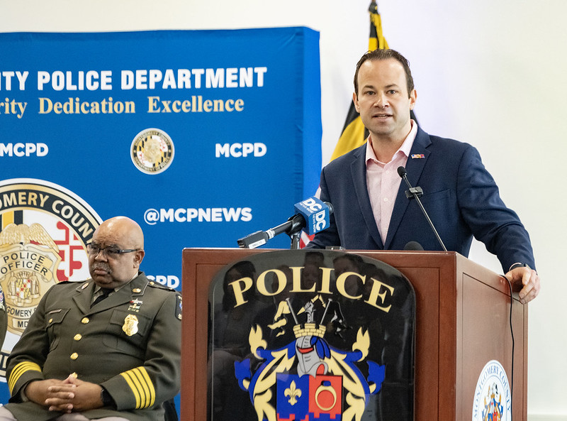 Le président du Conseil Friedson s'exprime depuis le podium de la MCPD, en présence du commissaire de police Jones assis derrière lui.