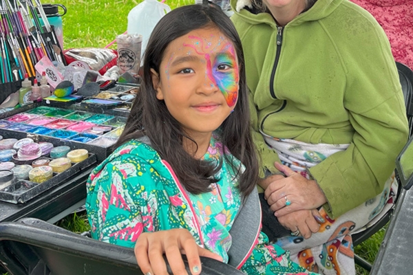 Young girl smiling as she is getting her face painted at the annual GreenFest event.