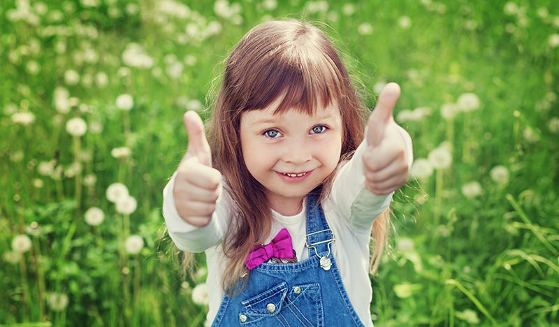 child-thumbs-up-with-grass-and-clover