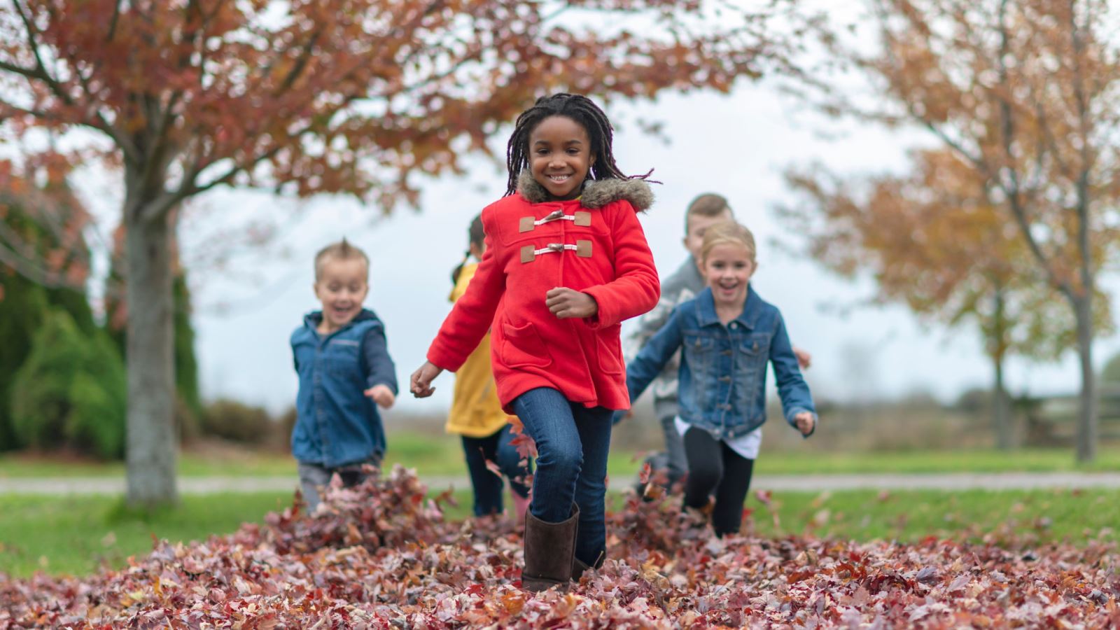children running through pile of autumn leaves