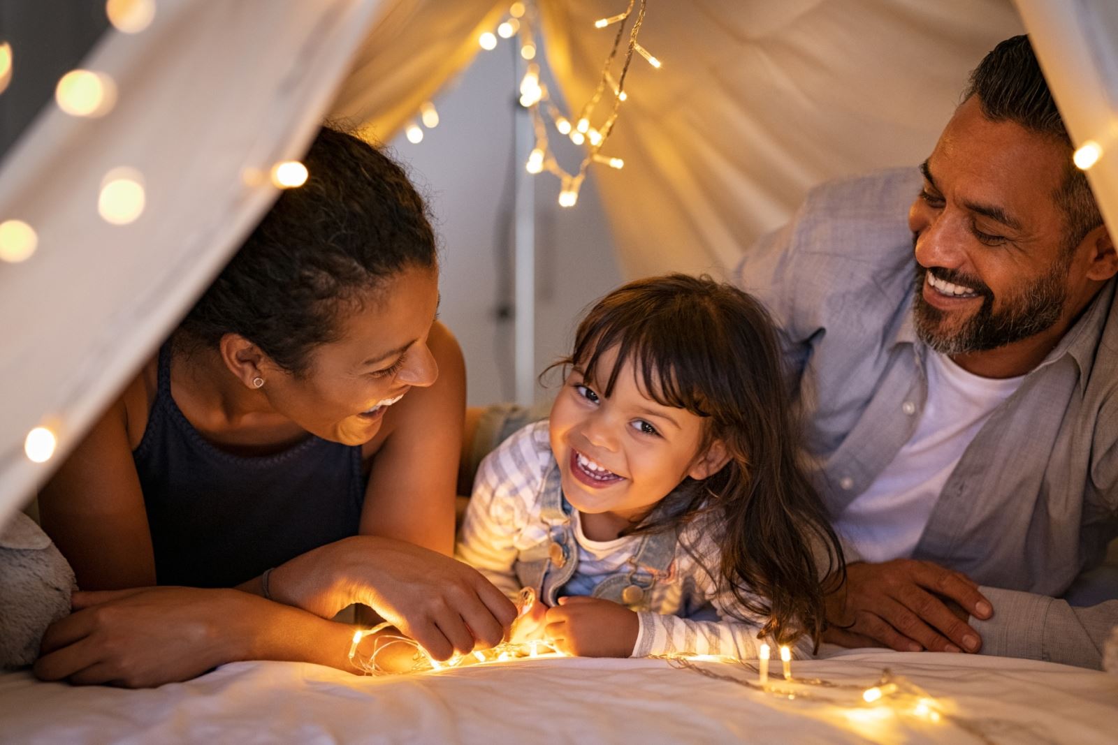 family under a small blanket tent indoors