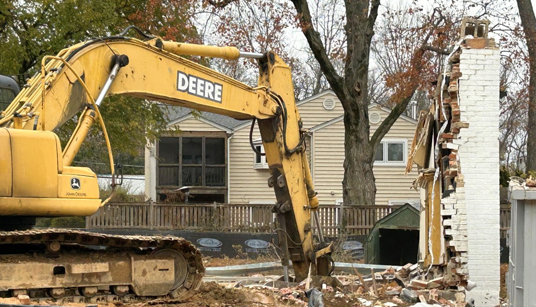 Photo of construction equipment picking up debris of a single-family home undergoing demolition