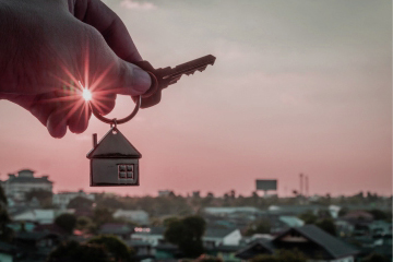 hand holding key with house keychain