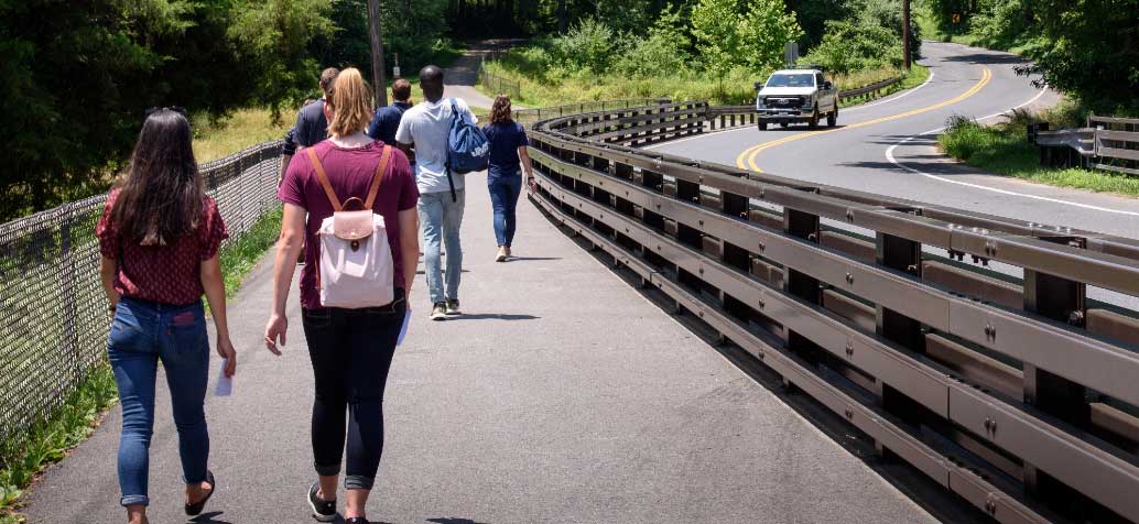 people walking on path next to guardrail