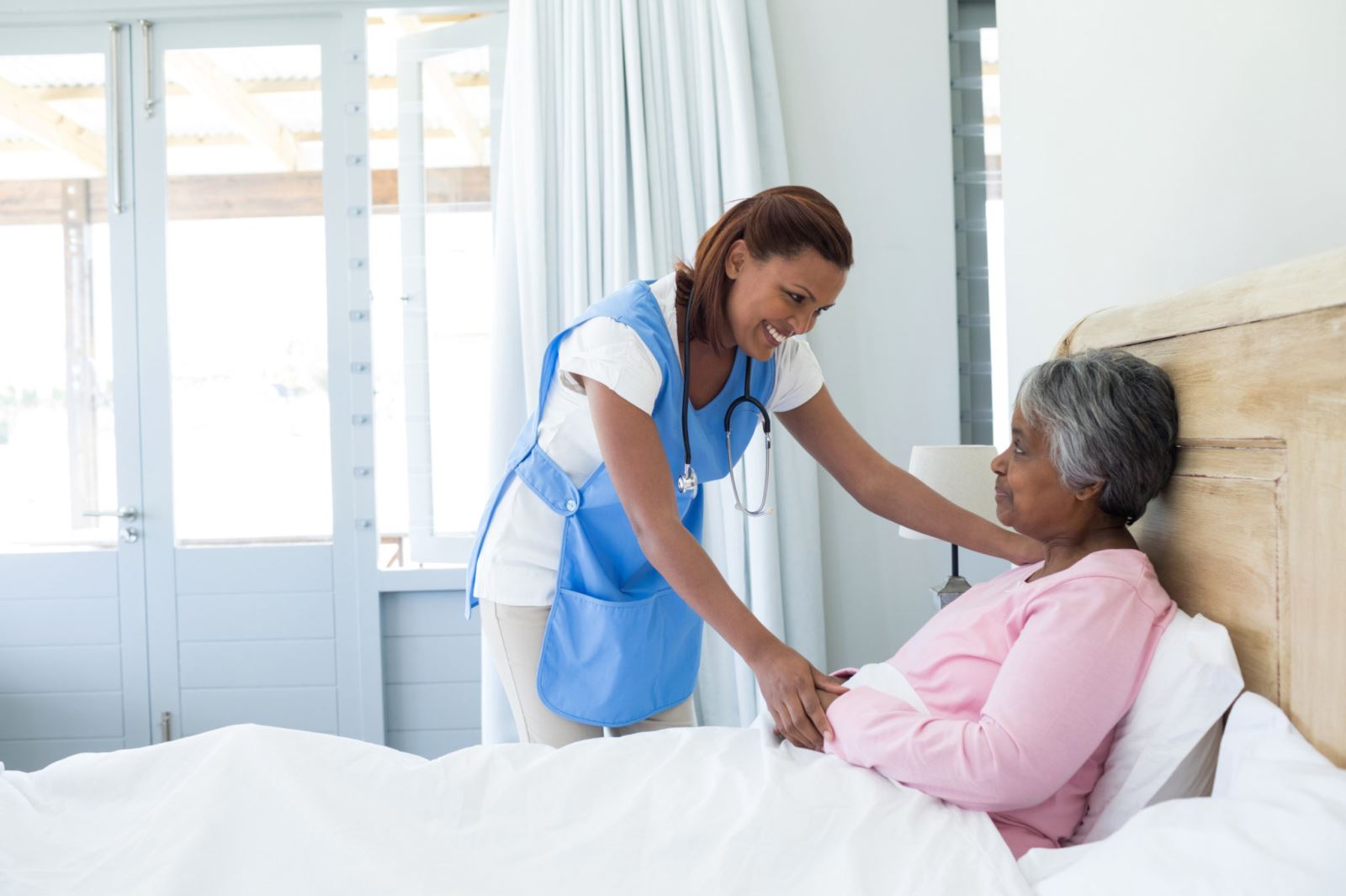 Nurse helping women in bed at an Assisted living facility