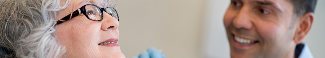 Dentist speaking with a mature patient during a dental exam.