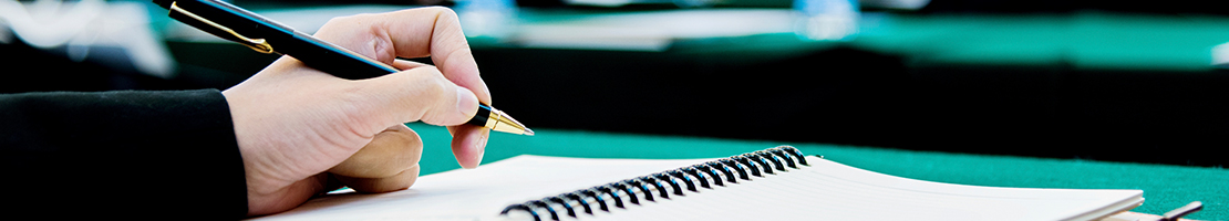 Hand holding a pen at a table writing.