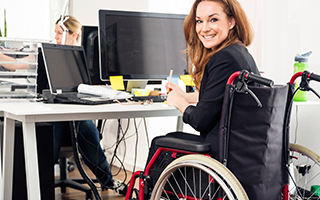 Professional women sitting in a wheel chair working at a computer.