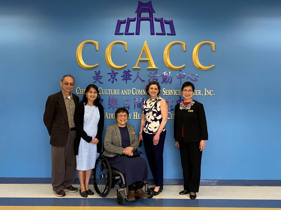 CP Stewart and CCACC leaders stand in front of CCACC logo with Chinese lettering.