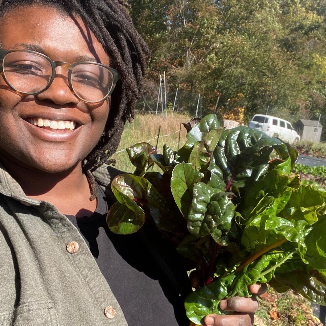 Farm manager Alicia at Afrithrive Farm, Poolesville holding leafy vegetables 