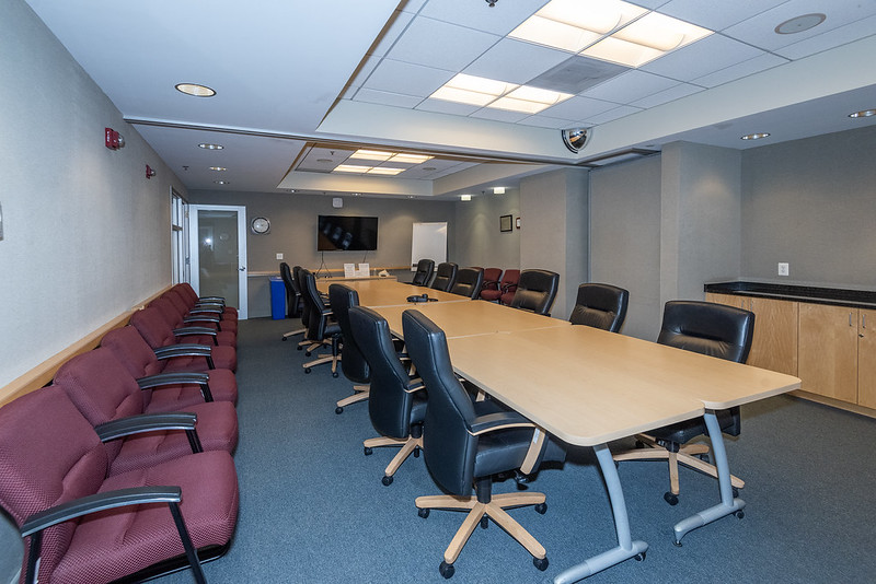 conference room with long central table surrounded by chairs, and a row of chairs against a wall