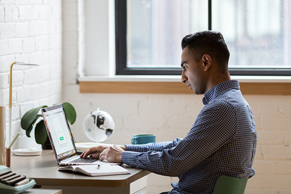 person looking into a laptop and holding a mobile phone