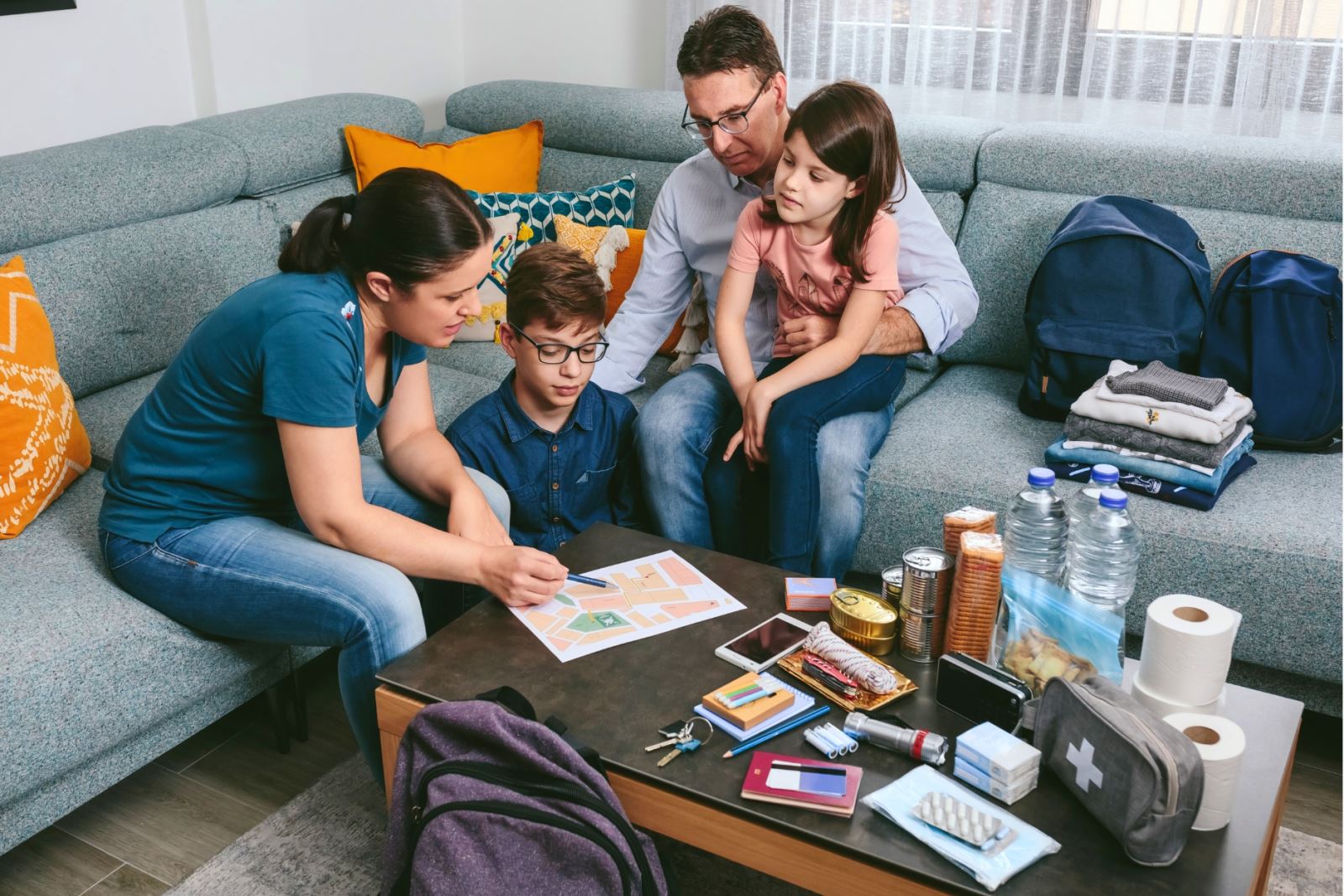 family gathering emergency supplies and reviewing emergency plans in living room