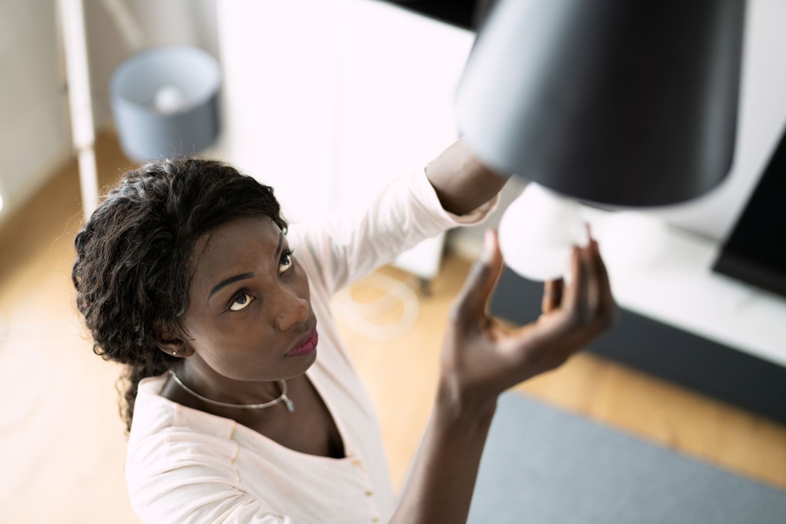 woman replacing light bulb in overhead fixture