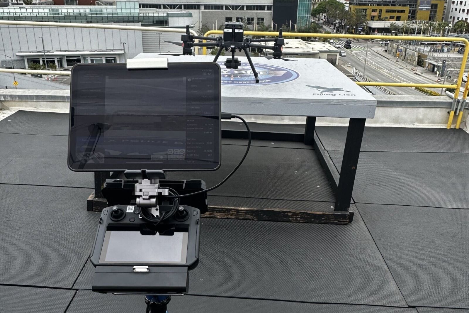 Photo pf a County drone sitting on a landing pad with a computer pilot station sitting adjacent to the pad. 