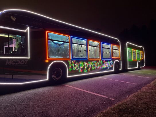 Ride on Bus with Happy Holidays lights around windows. 