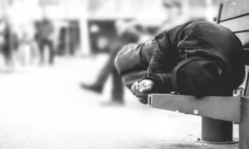 Photo of homeless person laying on a street bench.