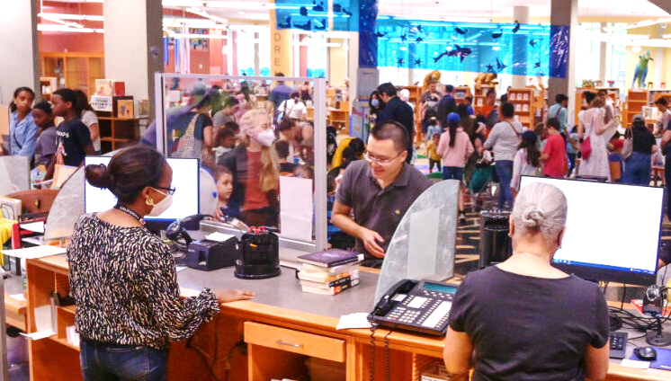 People walking and sitting at computers in a library. 