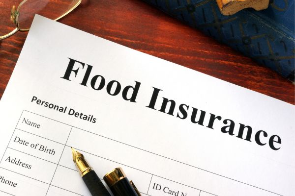 A desk with paper flood insurance application, eyeglasses and fountain pen.
