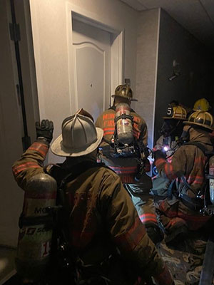 Fire fighter preparing to breach a door with other fire fighters