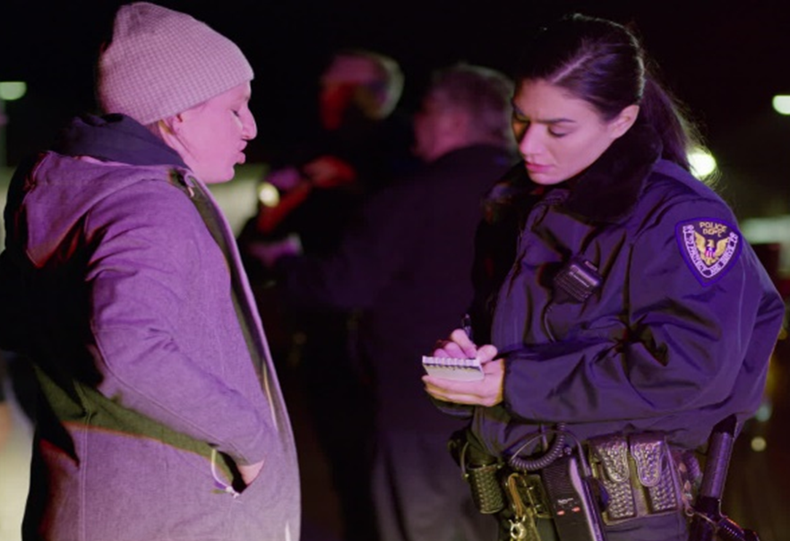 A woman being interviewed by a police officer.